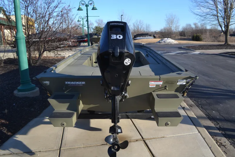 Slide: The Image of 2025 Tracker Grizzly 1654 T Sportsman boat with 30 HP motor, parked outdoors. - 2