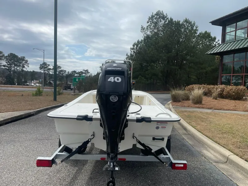 Slide: The Image of 2025 Mako Pro Skiff 13 CC boat on trailer with 40 HP motor, parked outdoors. - 2