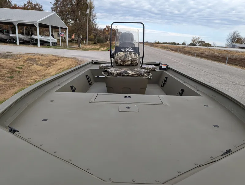 Slide: The Image of 2025 Tracker Grizzly 1860 CC boat, spacious deck, camo seat, rural setting. - 12