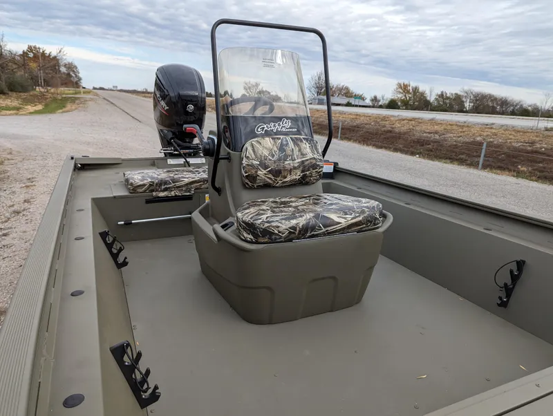 Slide: The Image of 2025 Tracker Grizzly 1860 CC boat with camouflage seats on a rural road. - 13