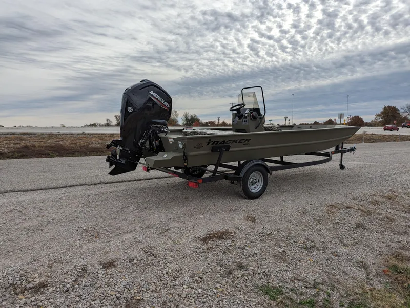 Slide: The Image of 2025 Tracker Grizzly 1860 CC boat on trailer, parked on gravel road under cloudy sky. - 6