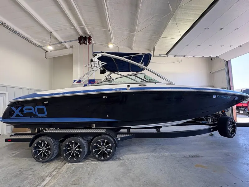 Slide: The Image of 2005 MasterCraft X-80 boat in a garage, black exterior, triple-axle trailer. - 5