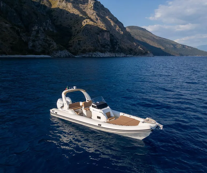 Slide: The Image of Nuova Jolly Prince 30 Exclusive 2025 boat on blue sea near rocky coastline. - 6