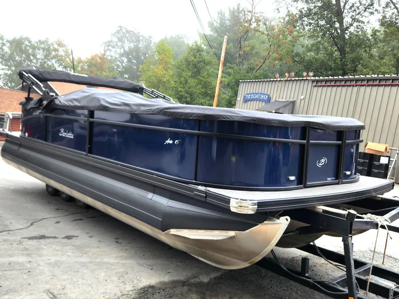 Slide: The Image of 2024 Barletta Aria 24QC pontoon boat, blue exterior, covered, on a trailer. - 3