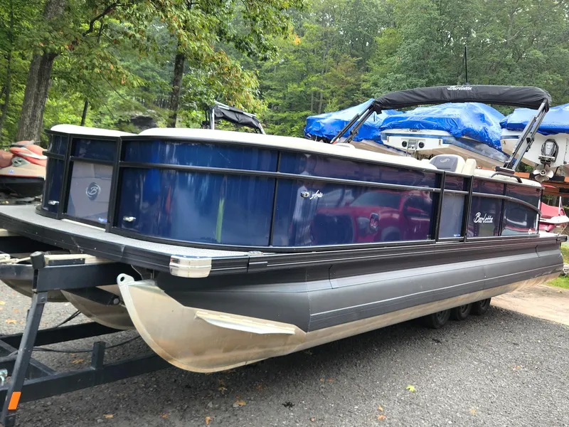 Slide: The Image of 2024 Barletta Aria 24QC pontoon boat on trailer, surrounded by trees. - 5