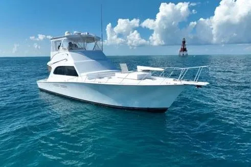 Slide: The Image of 1998 Post 50 Sportfish yacht on open sea with clear skies and distant lighthouse. - 0
