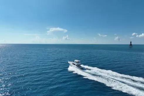 Slide: The Image of 1998 Post 50 Sportfish cruising on open blue ocean under clear sky. - 1