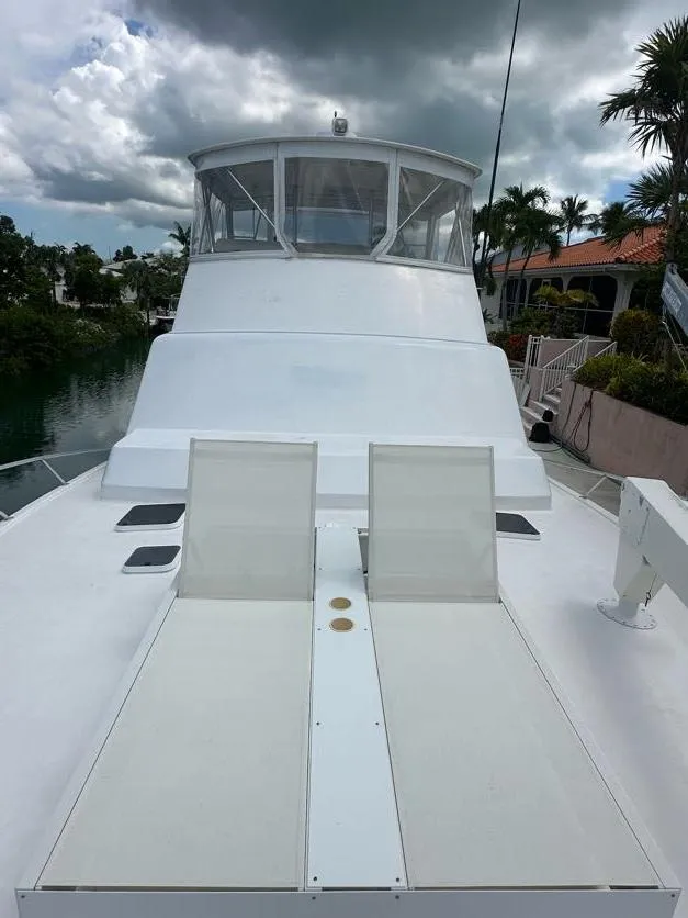 Slide: The Image of 1998 Post 50 Sportfish yacht with spacious deck and seating, docked near tropical foliage. - 21