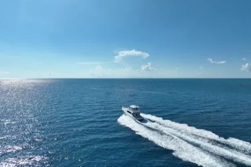 Slide: The Image of 1998 Post 50 Sportfish cruising on open ocean under clear blue sky. - 34