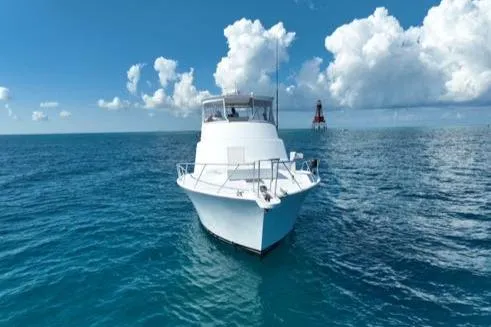 Slide: The Image of 1998 Post 50 Sportfish boat on open ocean under blue sky and clouds. - 38
