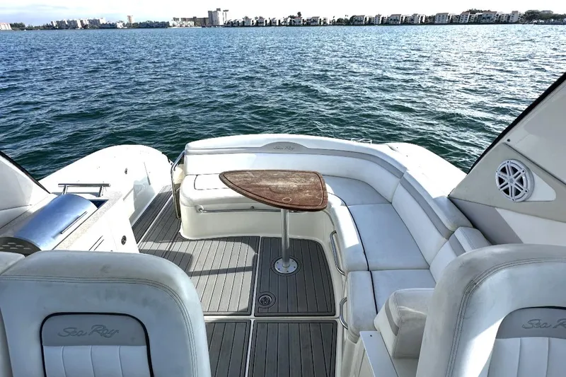 Slide: The Image of 2010 Sea Ray 370 Sundancer boat interior with white seating and wooden table on open water. - 20