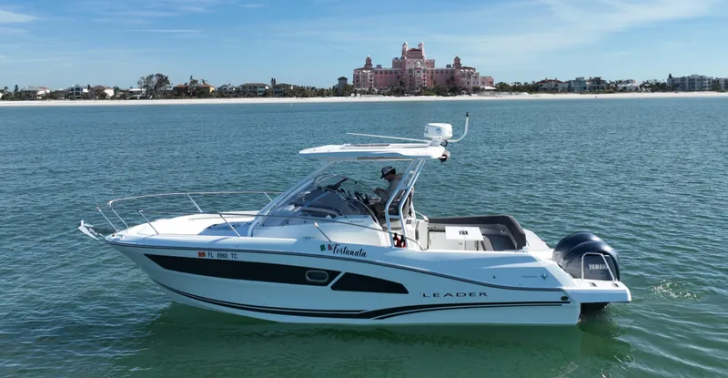 Slide: The Image of 2021 Jeanneau Leader 9.0 WA boat cruising on calm waters near a coastal building. - 2