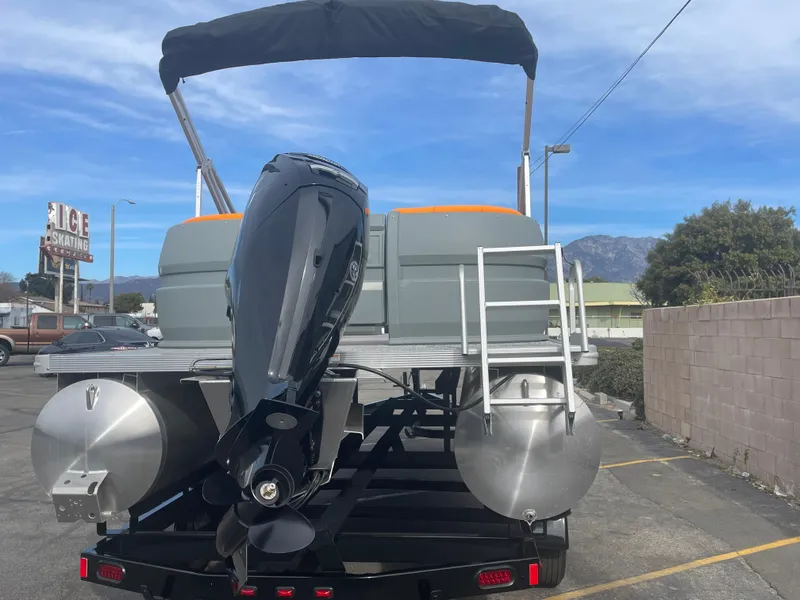 Slide: The Image of 2025 Avalon 21 AURA pontoon boat with outboard motor, parked outdoors. - 2