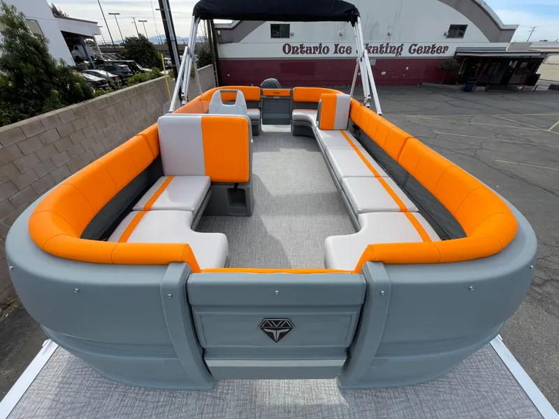 Slide: The Image of 2025 Avalon 21 AURA pontoon boat with orange and gray seating, parked near Ontario Ice Skating Center. - 3