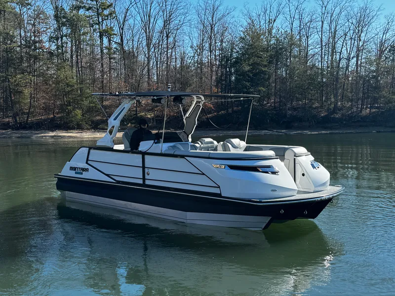 Slide: The Image of 2025 Montara Surf Boss 2.0 25 boat on a calm lake with forest backdrop. - 1