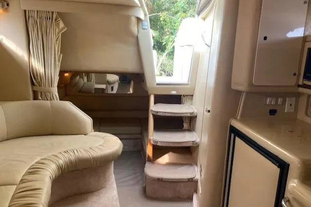 Slide: The Image of Interior of 1998 Sea Ray 330 Sundancer yacht, featuring beige seating and compact kitchenette. - 10