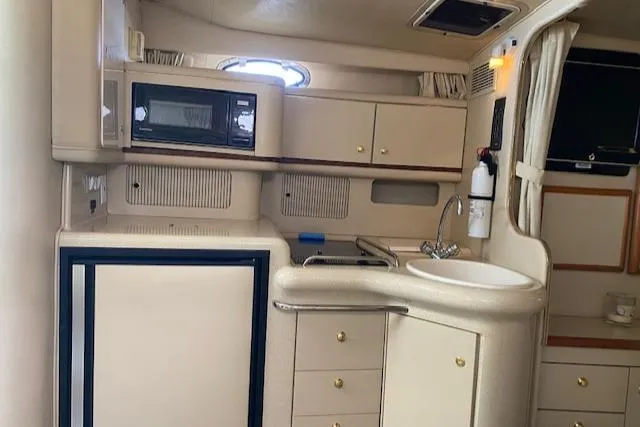 Slide: The Image of 1998 Sea Ray 330 Sundancer interior kitchen with sink, microwave, and storage cabinets. - 7