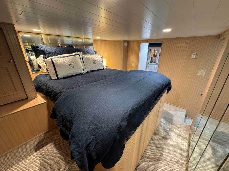 Slide: The Image of Cozy bedroom in 1997 Sumerset 85x18 houseboat with navy bedding and wood paneling. - 16