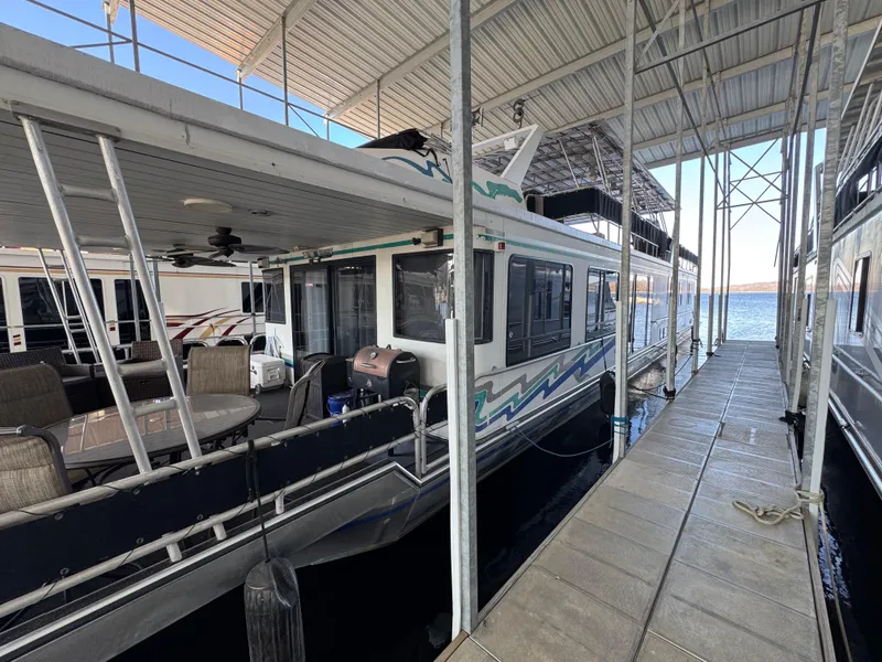Slide: The Image of 1997 Sumerset 85x18 houseboat docked, featuring spacious deck and covered mooring area. - 3