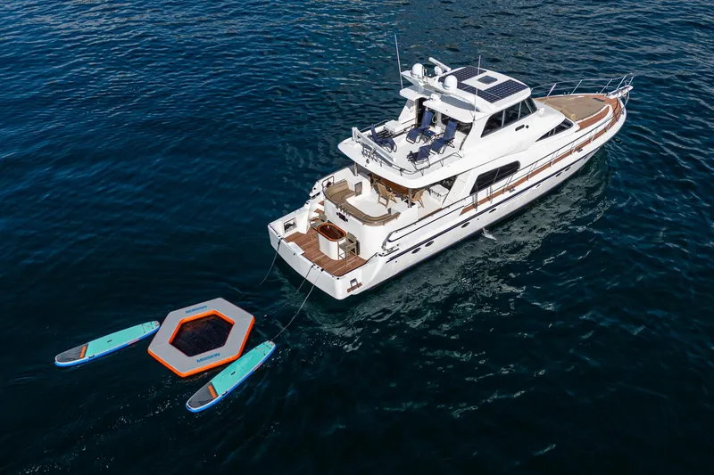 Slide: The Image of 2002 Johnson Pilothouse 70 Motor Yacht on water with paddleboards. - 24