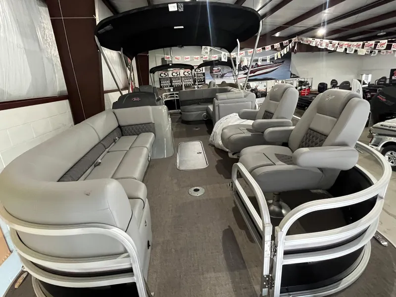 Slide: The Image of 2025 Ranger 223FC pontoon boat interior with gray seating and canopy in showroom. - 2