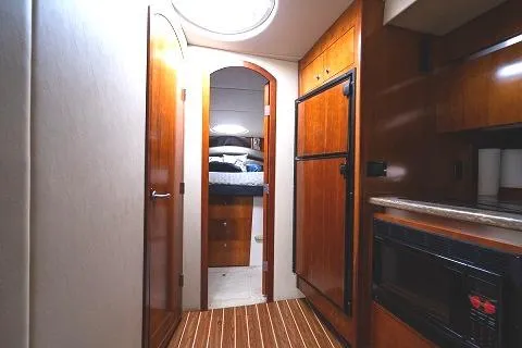 Slide: The Image of 2008 Cruisers 420 Express yacht interior with wood cabinetry, microwave, and cozy bedroom. - 20