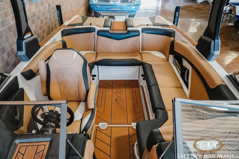 Slide: The Image of 2018 Tigé Z3 boat interior with tan and black seating, steering wheel, and Lake Norman Marina logo. - 12