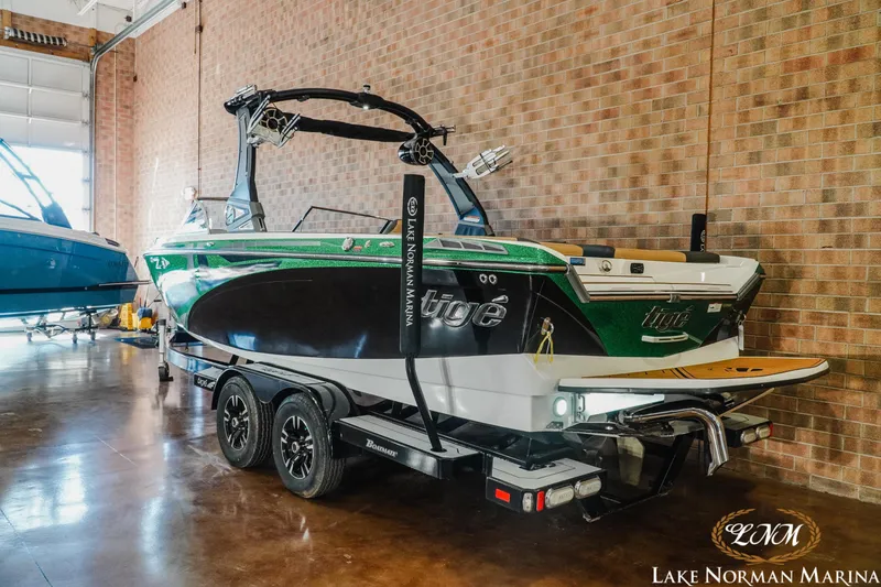 Slide: The Image of 2018 Tigé Z3 boat in a marina showroom, green and black design, on a trailer. - 2
