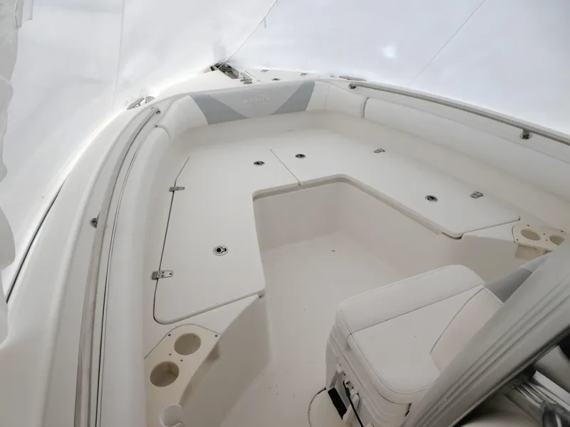 Slide: The Image of 2014 Boston Whaler 220 Outrage boat interior with white seating and storage compartments. - 14