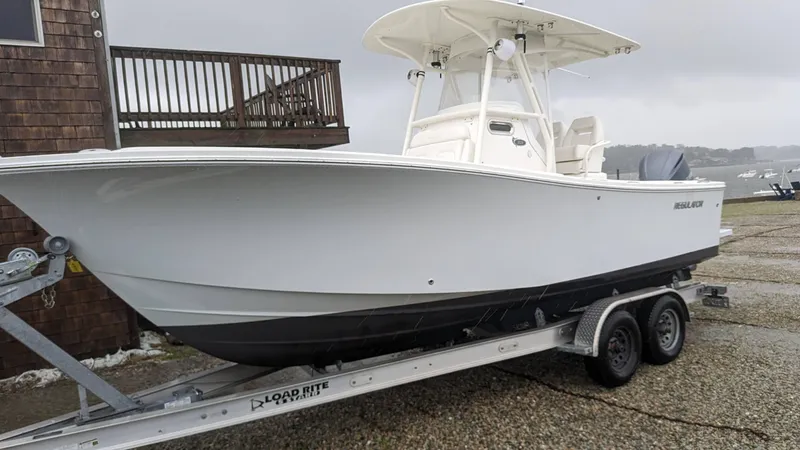 Slide: The Image of 2017 Regulator 23 boat on trailer, parked outdoors on a cloudy day. - 12