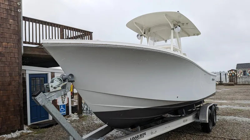 Slide: The Image of 2017 Regulator 23 boat on trailer, parked outdoors near wooden building. - 14