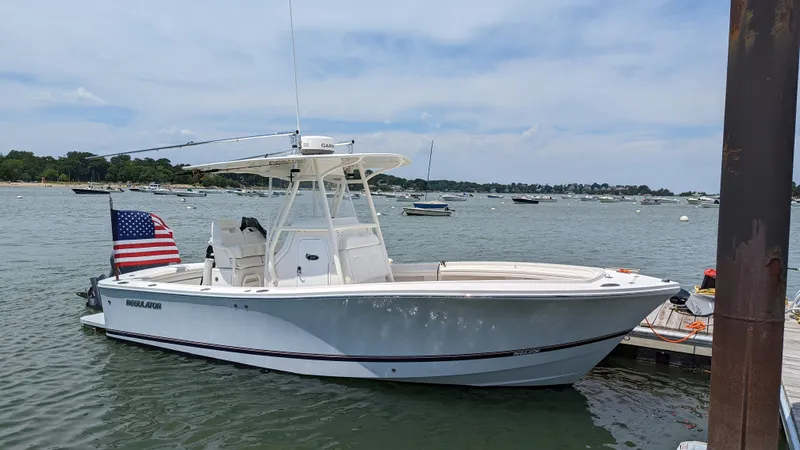 Slide: The Image of 2017 Regulator 23 boat docked with American flag, calm waters, and clear sky. - 4