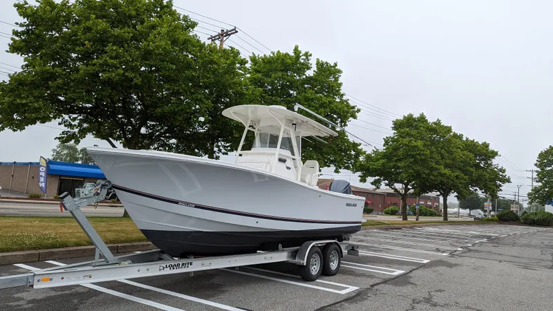 Slide: The Image of 2017 Regulator 23 boat on trailer in parking lot, surrounded by trees. - 5