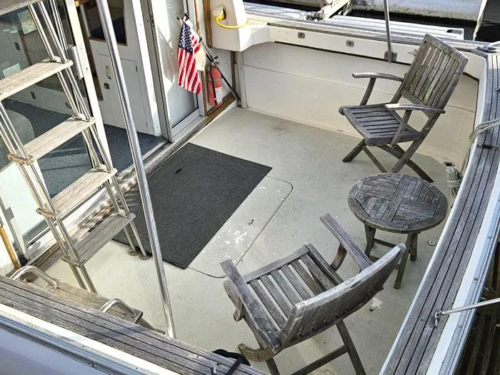 Slide: The Image of 1978 Mainship 34 Sedan boat deck with wooden chairs and American flag. - 4