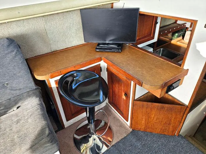Slide: The Image of 1978 Mainship 34 Sedan interior with a desk, chair, and monitor setup. - 8
