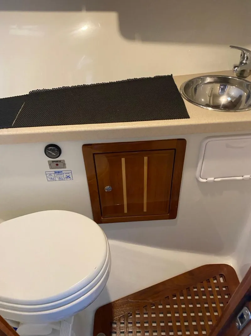 Slide: The Image of 2005 Ocean Sport Roamer 30 boat bathroom with sink, toilet, and wooden cabinet. - 13