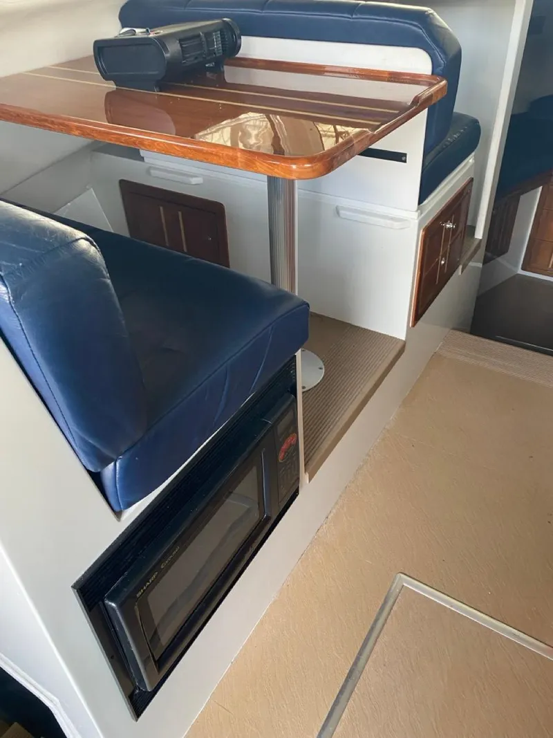 Slide: The Image of 2005 Ocean Sport Roamer 30 interior with blue seating, wooden table, and built-in microwave. - 9