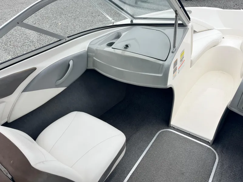 Slide: The Image of 2009 Bayliner 185 boat interior with white seating and gray dashboard. - 17