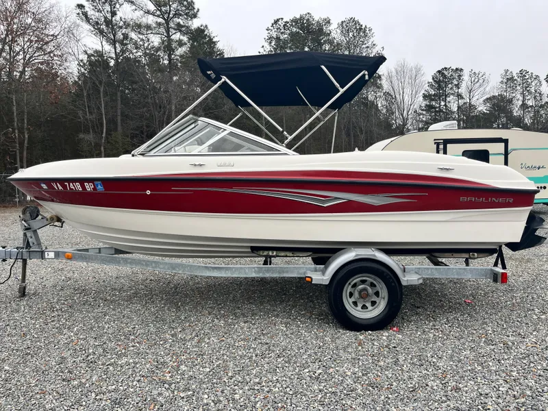 Slide: The Image of 2009 Bayliner 185 boat with red and white design on a trailer, parked outdoors. - 8