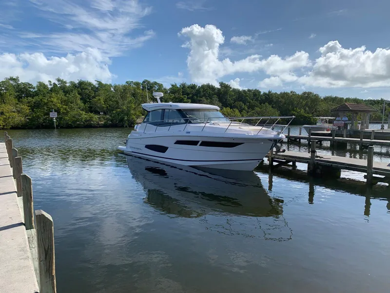 Slide: The Image of 2021 Regal 38 XO yacht docked on a serene lake under a blue sky. - 35