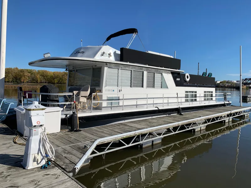The Image of 1977 Gibson Standard houseboat docked on a sunny day, featuring a spacious deck and modern amenities. - 0
