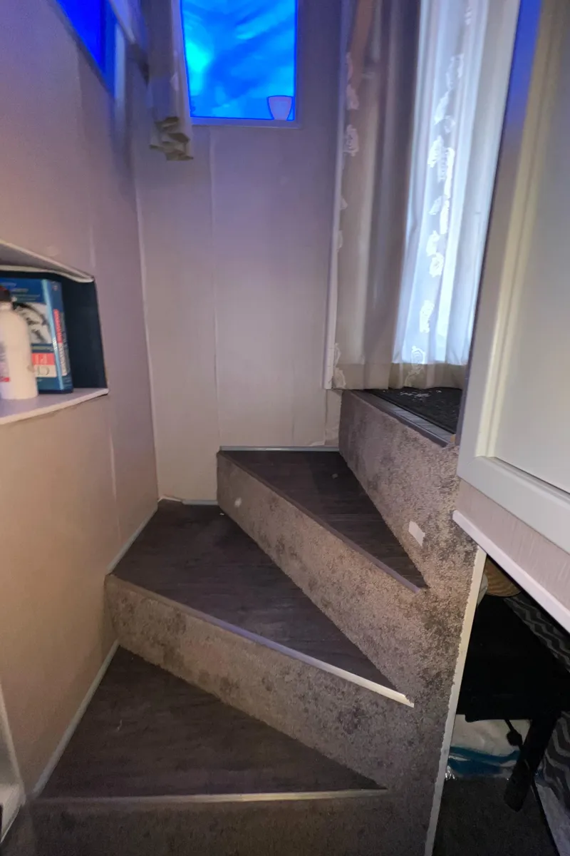 Slide: The Image of Carpeted stairs with a window and shelf, featuring a cozy, narrow design. - 11