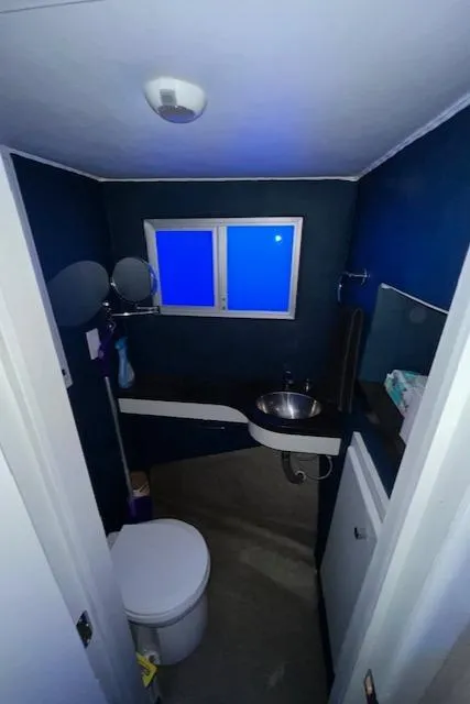 Slide: The Image of Small modern bathroom with blue walls, round mirror, and compact fixtures. - 12