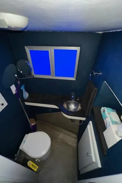 Slide: The Image of Compact bathroom with blue walls, modern fixtures, and a small window. - 13