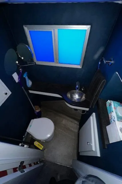 Slide: The Image of Compact bathroom with blue walls, modern fixtures, and a small window. - 16