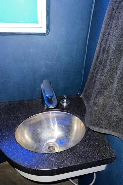 Slide: The Image of Modern bathroom sink with dark countertop and towel, blue wall background. - 17