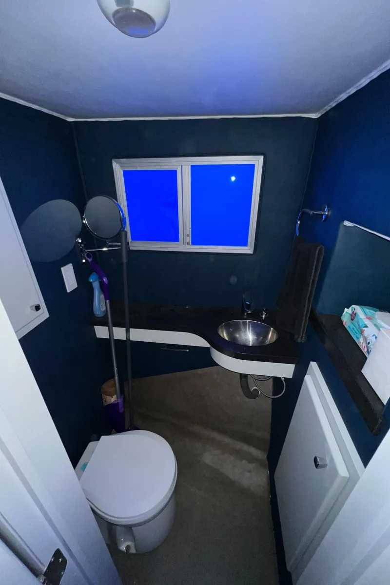 Slide: The Image of Small bathroom with dark blue walls, modern fixtures, and a window. - 19