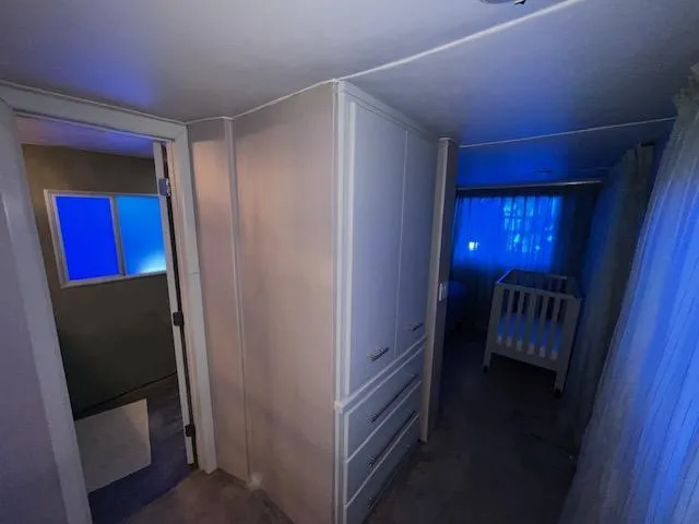 Slide: The Image of A dimly lit room with a crib, blue lighting, and white cabinetry. - 20