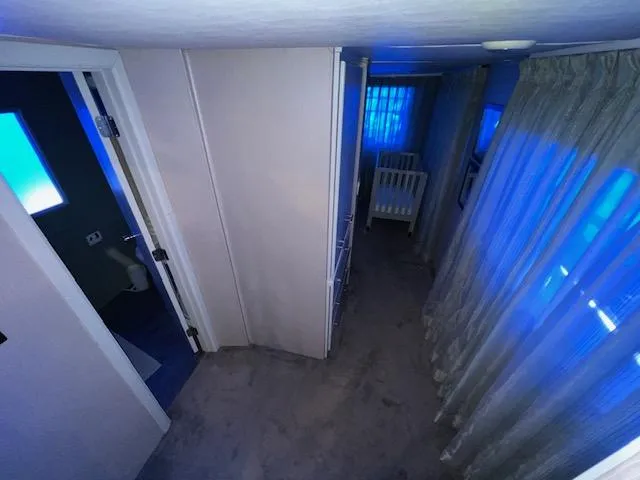 Slide: The Image of A dimly lit hallway with a crib and blue lighting. - 21