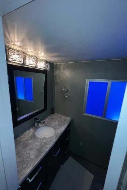 Slide: The Image of Modern bathroom with marble countertop, mirror, and blue-tinted window lighting. - 23